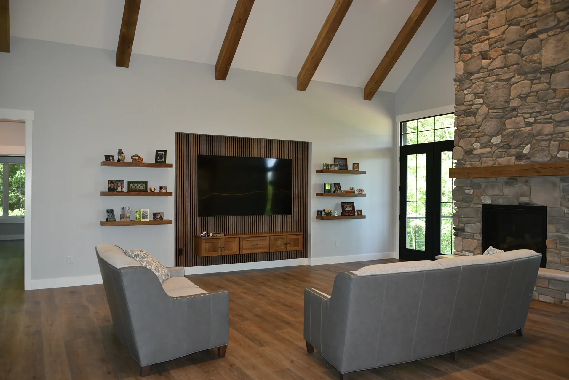 A modern living room with grey couches and a TV mounted on a wooden accent wall.